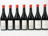 six bouteilles de vin rouge alignées sur une surface blanche