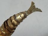 un objet de couleur dorée sur lequel figure un poisson, au niveau de la tête