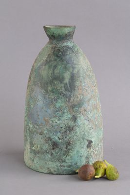 un vase vert avec quelques fruits sur la table