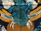 une image représentant une nappe bleue et dorée sur laquelle est posé un vase de fleurs