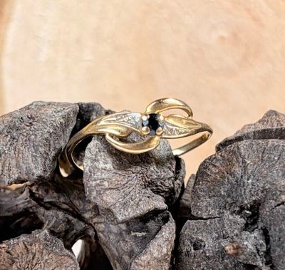 une bague en or sertie d'une pierre noire, posée sur un tas de pierres