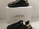 une paire de chaussures noires et dorées sur lesquelles est inscrit le mot « Guess »