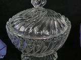 an image of a glass bowl with a lid sitting next to a purple flower
