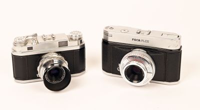 two cameras sitting next to each other on a white surface