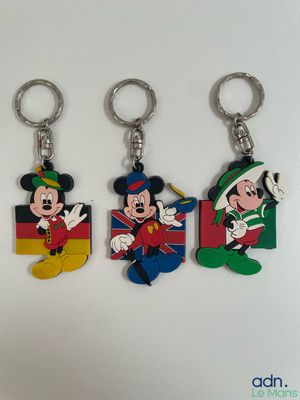 three mickey mouse and mickey mouse keychais on a white surface