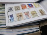 a person holding a stack of stamps on top of a pile of books