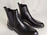une paire de bottines Chelsea en cuir noir sur fond blanc