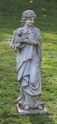 une statue représentant une femme tenant un chien dans un champ herbeux