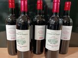six bouteilles de vin rouge sont alignées sur une table