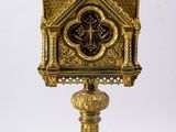 a gold clock on a stand with a cross on top