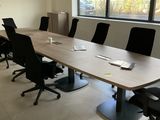 une longue table avec des chaises et un ordinateur portable posé dessus, dans une pièce