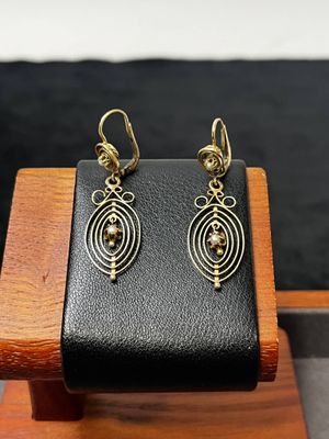 un gros plan sur une paire de boucles d'oreilles posées sur un support en bois