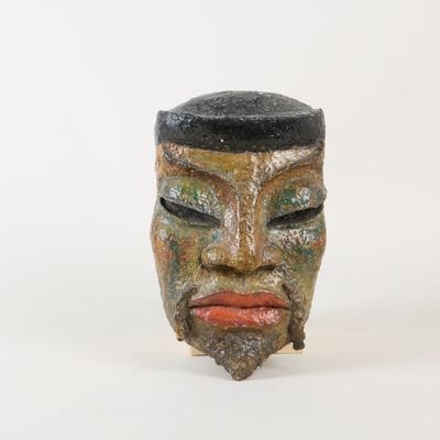 un masque en céramique coiffé d'un chapeau noir