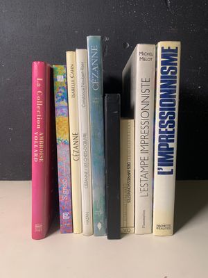 Plusieurs livres sont alignés sur une étagère devant un mur noir