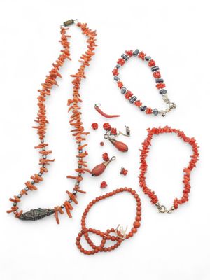 an assortment of coral necklaces and bracelets on a white surface