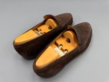 une paire de chaussures en daim marron à semelles en bois, posées sur une surface grise