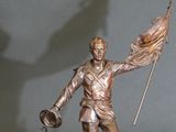 bronze statue of a man holding a flag and a flag pole