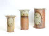 three vases sitting next to each other on a white surface