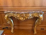 une console en or richement décorée, dotée d'un plateau en marbre, dans une pièce