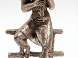a silver statue of a man sitting on a bench