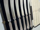 a case with six knives in it on a table