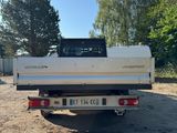 the back end of a white truck parked in a dirt lot