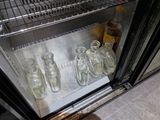 several empty glass bottles are lined up on a shelf in a refrigerator