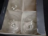 four empty wine glasses in a box on a table