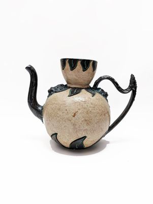 une théière noire et blanche posée sur une surface blanche