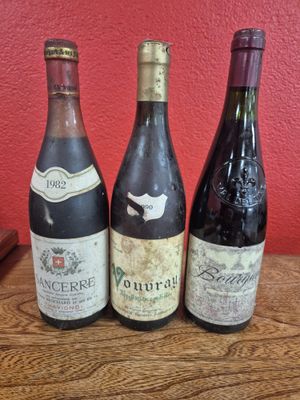 three bottles of wine sit on a table in front of a red wall