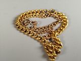 a close up of a gold chain bracelet with a heart on it