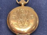 an old gold pocket watch with a chain on a blue surface