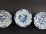 three blue and white plates with flowers on them on a black background