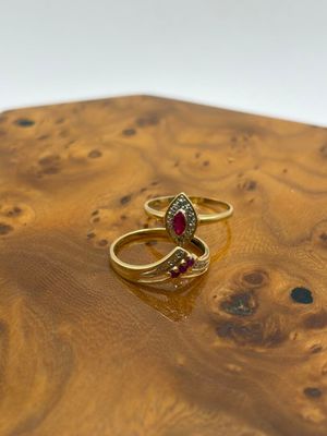 pair of gold rings with garnetts on top of a piece of wood