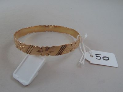 gold bracelet with butterfly design and tag on white surface