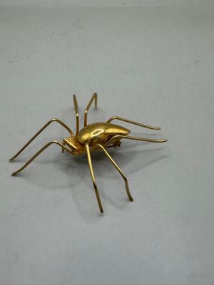 a gold spider that is sitting on a white surface