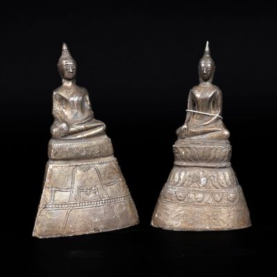a pair of silver buddha statues sitting on top of a table