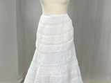 une robe blanche posée sur un présentoir à mannequin, avec un rideau blanc en arrière-plan