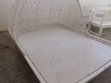 un lit en osier blanc dans une pièce avec des chaises blanches