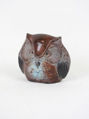 a small owl figurine sitting on a white surface