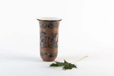 un petit vase avec une feuille par terre