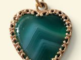 a green heart shaped pendant with a gold plated frame
