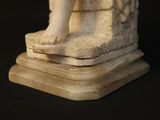 a statue of a child sitting on top of a stone block