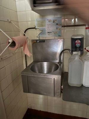 un évier dans un coin d'une cuisine où s'entassent de nombreuses bouteilles