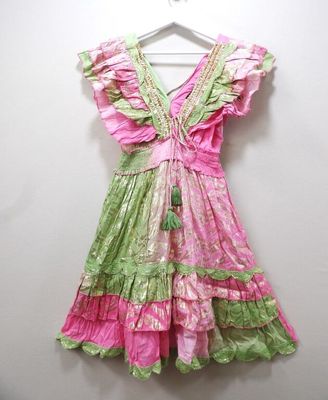 pink and green dress hanging on a hanger against a white wall