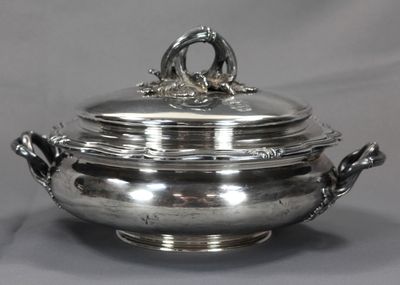 un plat en argent muni d'un couvercle et de poignées, sur fond gris