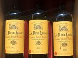 three bottles of red wine in a cardboard box on a table