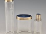 three clear glass containers with gold trims and a blue lid