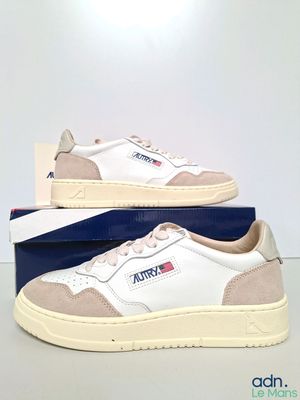 Les baskets blanches et beiges sont posées sur une boîte bleue.