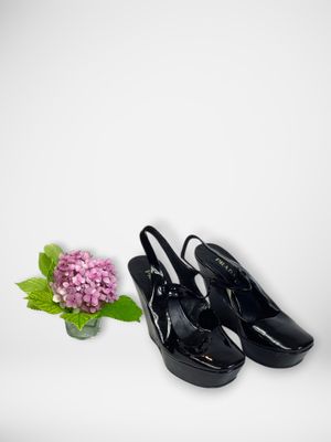 black high heeled shoes next to a vase with a flower